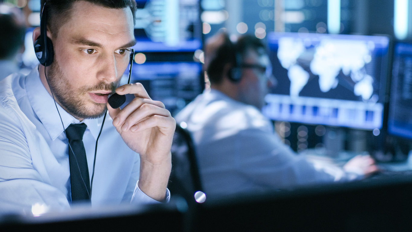 Operations professional wearing a headset in a multi-screen monitoring environment